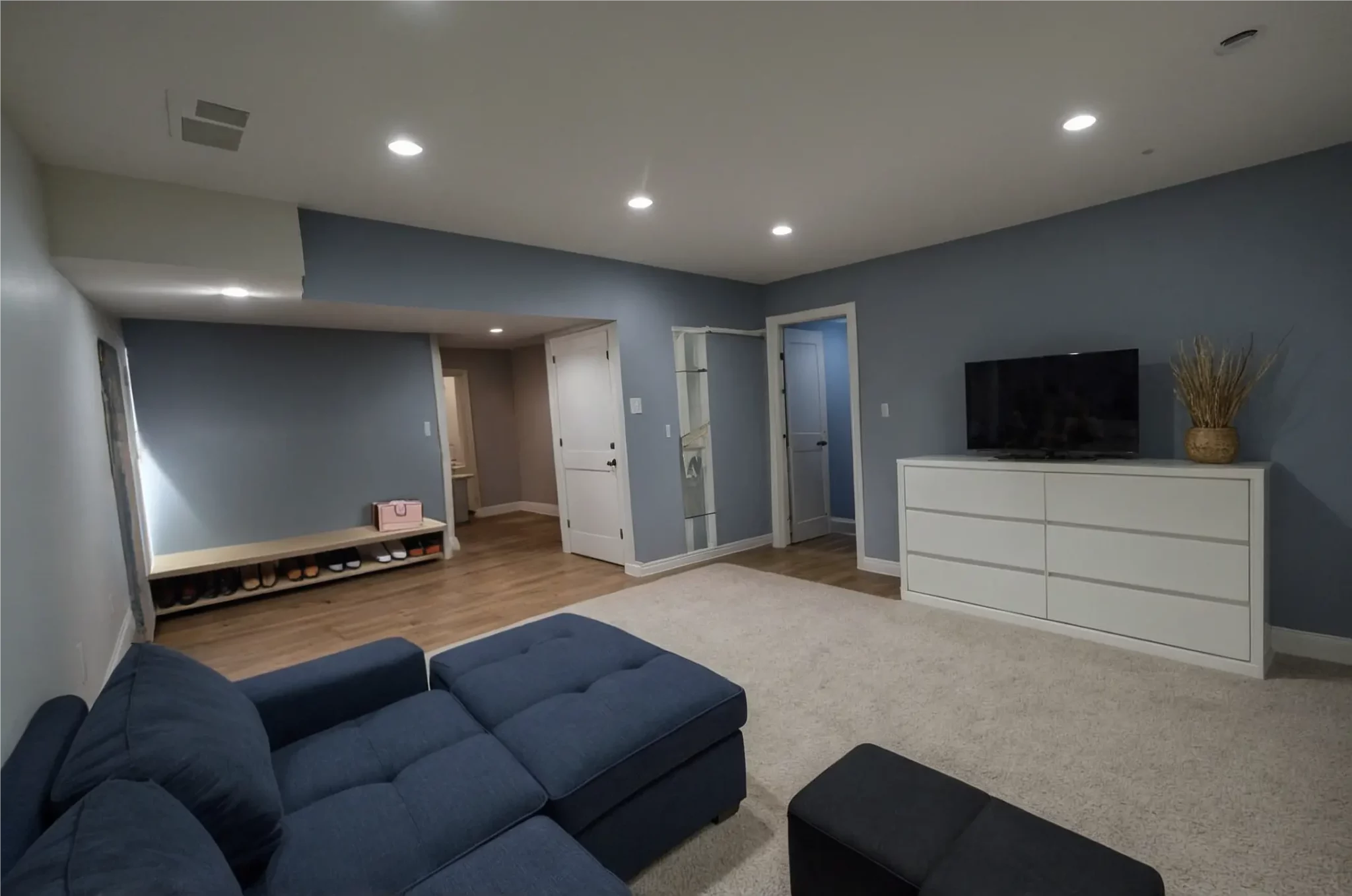 A finished basement family room with a large sectional and media wall